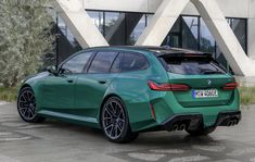 a green bmw car parked in front of a building