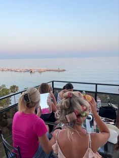 some people sitting at a table with donuts in their hair and looking out over the water