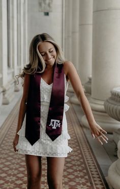 a woman in a white dress and maroon stole walking down a hall with her hand on the ground