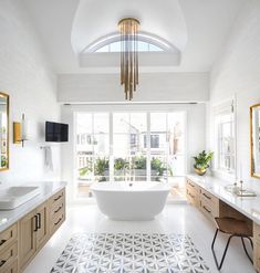 a large white bath tub sitting in a bathroom next to two sinks and a mirror