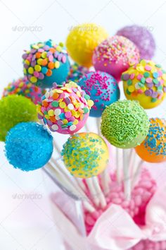 there are many colorful cake balls hanging from the ceiling and in front of a white background