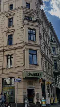 a tall building with lots of windows on the top floor and two people walking in front