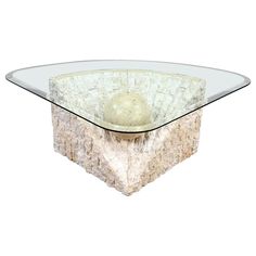 a glass and stone coffee table with a ball in the center, on an acrylic base