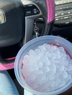 a plastic cup filled with ice sitting next to a steering wheel