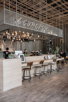 an open air cafe with wooden tables and stools in front of the counter area