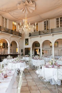 an indoor wedding venue with chandeliers and tables