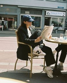 a woman sitting at a table reading a newspaper