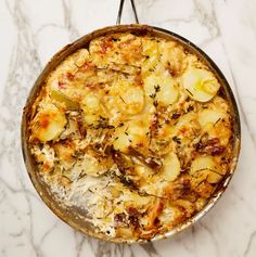 a pan filled with food sitting on top of a white marble countertop covered in lots of toppings