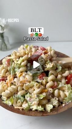 a wooden bowl filled with pasta salad on top of a table