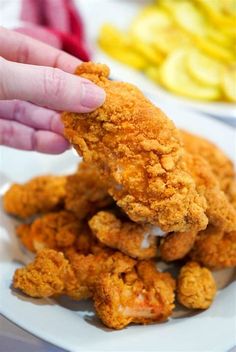 a person reaching for some fried food on a plate