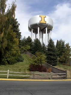 a large water tower sitting on top of a lush green hillside next to a forest