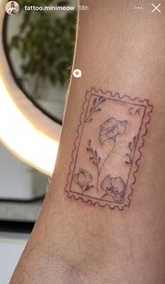 a small tattoo on the arm of a man with flowers in a frame and leaves