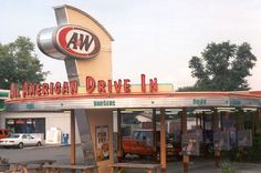 an american drive - in restaurant with picnic tables and cars parked at the front entrance