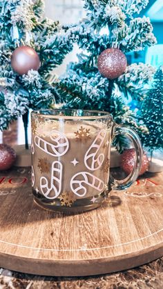 a glass mug sitting on top of a wooden table next to christmas tree branches and ornaments