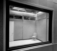 a white chair sitting in front of a mirror on the side of a wall next to a doorway