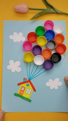 a child's hand is painting a house on paper