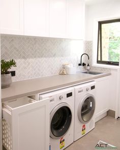 a washer and dryer in a white kitchen with an open door leading to the outside