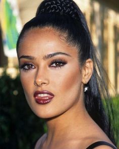 a close up of a woman with long hair and makeup on her face, wearing red lipstick