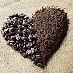 two pieces of chocolate and ground coffee in the shape of a heart on a wooden surface