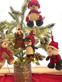 a christmas tree decorated with teddy bears and other knitted items in a tin can