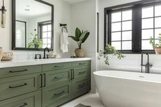 a bathroom with green cabinets and a white bathtub