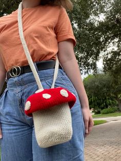 a woman is holding a red mushroom purse