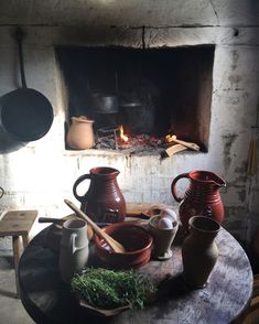 pots and pans are sitting on a table in front of an open fire place