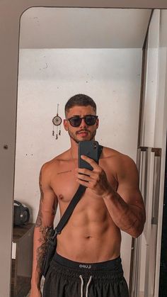 a shirtless man taking a selfie in front of a mirror with his cell phone