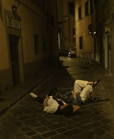 two people laying on the ground in an alley