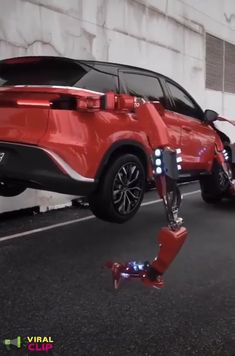 an image of a robot that is in the street next to a car and another vehicle