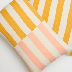 two yellow and white striped pillows sitting next to each other