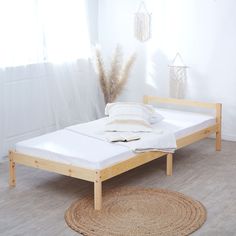 a bed sitting on top of a hard wood floor next to a white wall and window