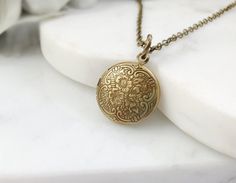 "This little locket necklace is made with a 15mm round, antiqued bronze floral locket, perfect to hold tiny photos, and it hangs on an 18-inch antiqued bronze cable chain with a lobster clasp. This lovely Victorian necklace makes the perfect romantic jewelry gift for her. Thank you for looking. NOTE: Gemsicles' gold-filled, rose/gold-plated, antiqued, silver and rhodium jewelry is cadmium-free, lead-free and nickel-free. Also, our plated jewelry is dipped in a special coating to help prevent tar Bronze Round Pendant Necklace For Wedding, Antique Gold Brass Necklace For Wedding, Antique Gold Necklace With Antique Finish For Wedding, Antique Gold Wedding Necklace With Antique Finish, Adjustable Antique Gold Locket Jewelry, Adjustable Antique Gold Necklace With Vintage Charm, Antique Gold Filigree Necklaces, Bronze Vintage Charm Necklace For Wedding, Adjustable Antique Gold Engraved Necklace