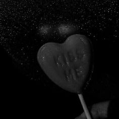 a heart shaped lollipop is being held by someone's hand in the dark