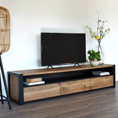 an entertainment center with a flat screen tv on it's stand, next to a plant