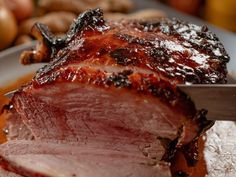 a close up of meat on a plate with potatoes and carrots in the background