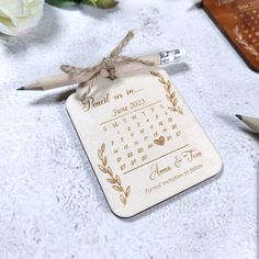 a personalized wooden calendar ornament on a table next to some pens and flowers