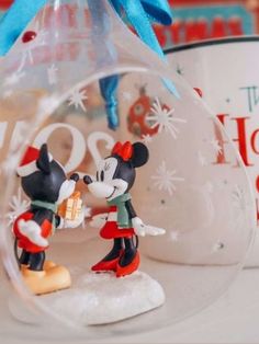 mickey and minnie mouse figurines in a glass ornament on a table