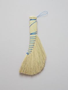 a piece of straw with blue string attached to it on a white surface next to a gray wall