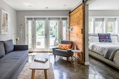 a living room filled with furniture and a wooden door leading to a bedroom next to a bed