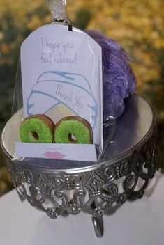 there are two donuts on the table with a note attached to it and a purple ball of yarn in the background