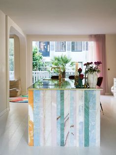 a kitchen island with marble counter tops and colorful stripes on the top, along with potted plants