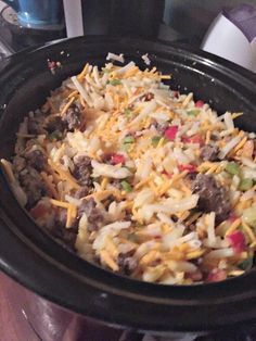 a crock pot filled with shredded cheese and other food items on top of a table