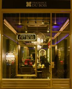 a store front with chandeliers in the window and lights on it's sides