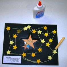 a black paper with stars and writing on it next to a bottle of glue that says paint