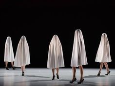 three women in white dresses and high heels walking on a stage with veils over their heads