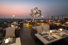 an outdoor dining area overlooking the city at dusk with lit candles on tables and chairs