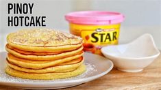 a stack of pancakes sitting on top of a white plate next to a container of syrup