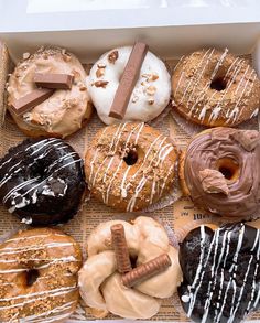 a box filled with lots of donuts covered in frosting and chocolate toppings