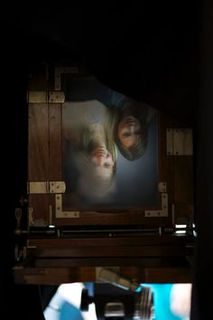 two people looking at a television screen with their faces reflected in the reflection on it